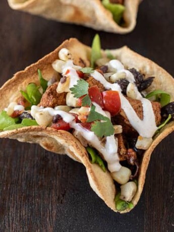 Chicken tostada Salad Bowl on a board with colorful corn, tomato, cilantro
