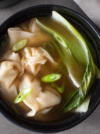 Green bok choy, sliced spring onions and chicken wontons on broth