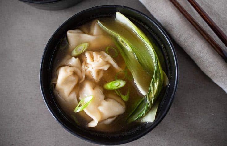 Green bok choy, sliced spring onions and chicken wontons on broth