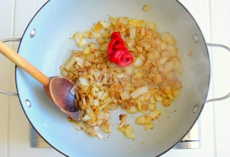 Tomato paste is added to onions and Indian spices