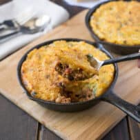 Scooping chili polenta pie out of a skillet