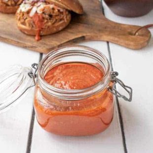 A jar full of bbq sauce with a pulled pork sandwich