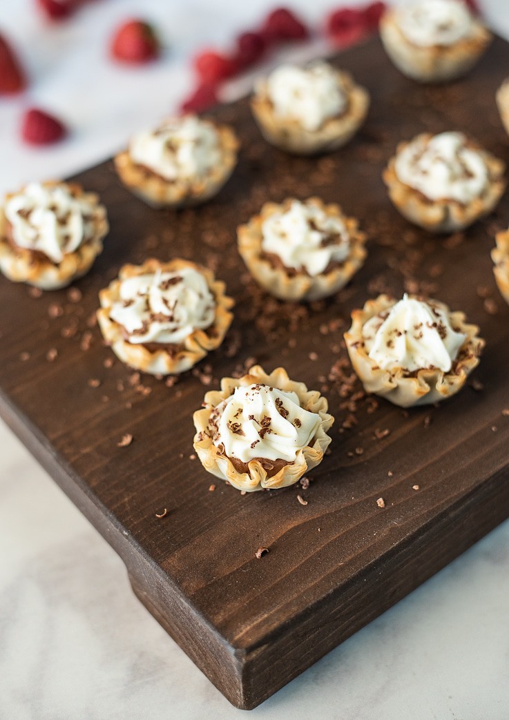 A closeup of Chocolate mousse and vanilla phyllo dessert cups on a brown serving board