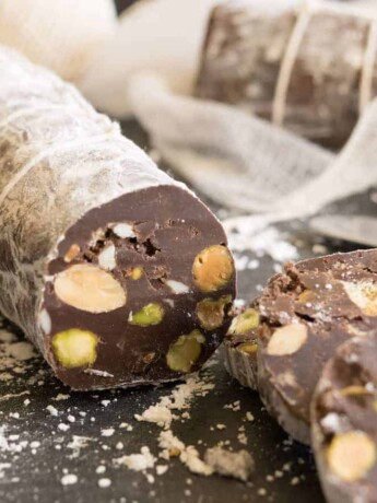 A closeup of a cut chocolate salami with nuts and cookie inside. Made to look like meat salami