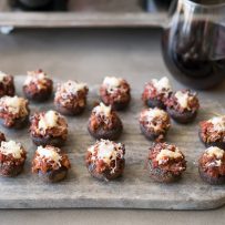 A platter of chorizo stuffed mushrooms with a glass of red wine