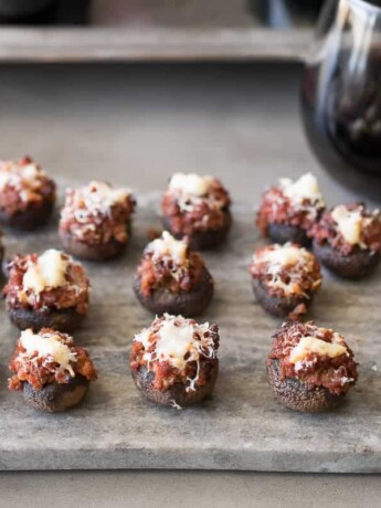 A platter of chorizo stuffed mushrooms with a glass of red wine