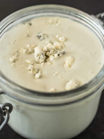 A closeup showing blue cheese crumbles in salad dressing
