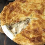 A golden, flaky pastry on top of creamy chicken and mushroom filling in a pie dish