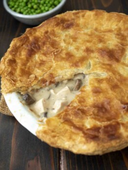 A golden, flaky pastry on top of creamy chicken and mushroom filling in a pie dish