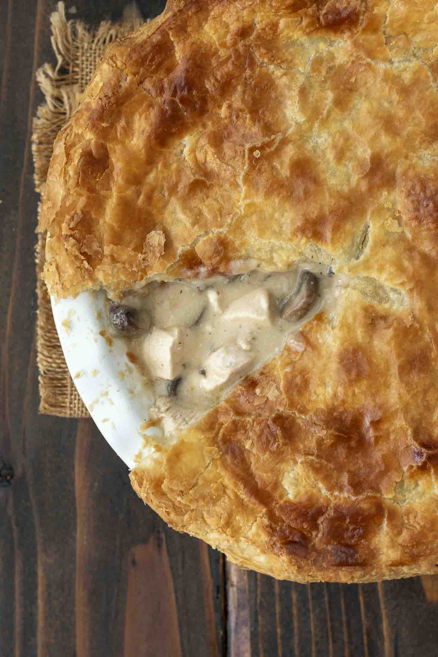 An overhead image of a piece of chicken and mushroom pie missing from the pie dish showing the filling