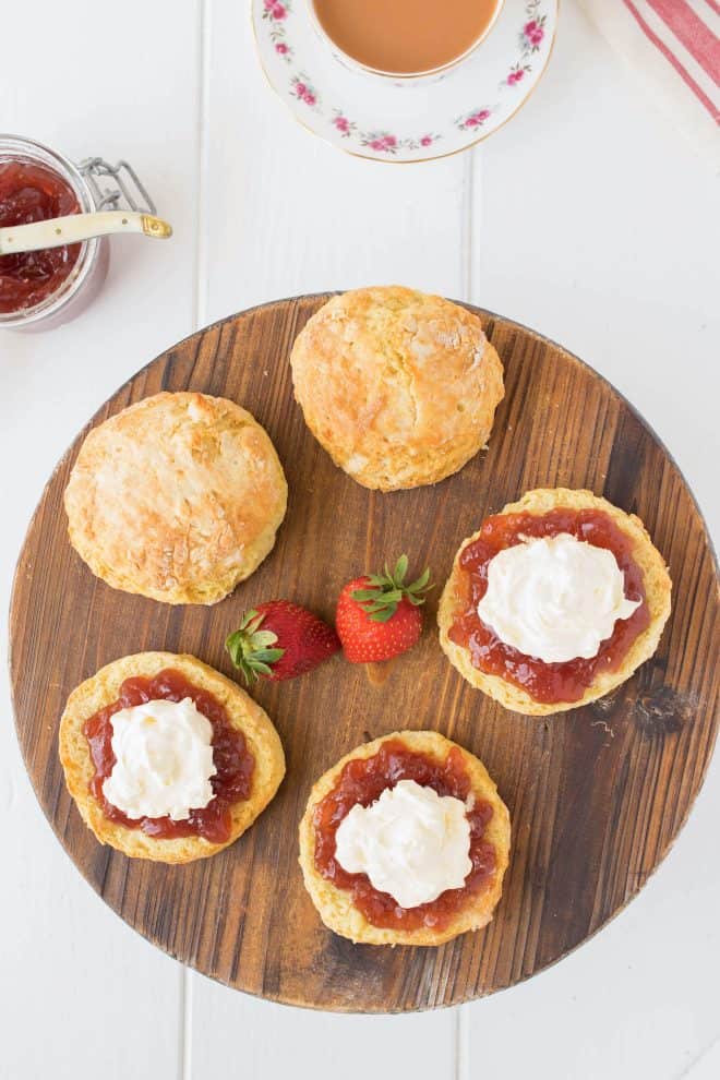 A round board of scones with jam and cream