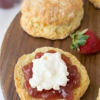 The bottom half of a scone topped with jam and clotted cream