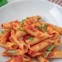 A closeup showing the tomato sauce on the pasta and fresh basil