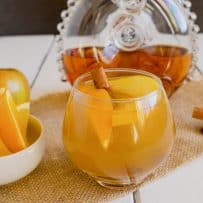 Orange wedges in a bowl and also in a cognac apple cocktail in a glass