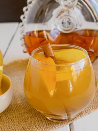 Orange wedges in a bowl and also in a cognac apple cocktail in a glass