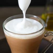 Pouring milk foam on top of a cup of coffee