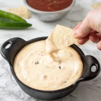 Dipping a tortilla chip into a bowl of queso blanco