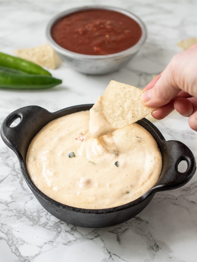 Dipping a tortilla chip into a bowl of queso blanco