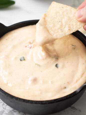 Dipping a corn tortilla chip into cheese queso