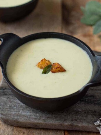 A bowl of cornbread, sage and onion soup on a serving platter with a spoon