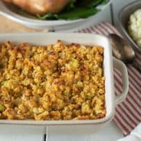 Cornbread, sage & onion stuffing in a roasting pan with a roast turkey behind