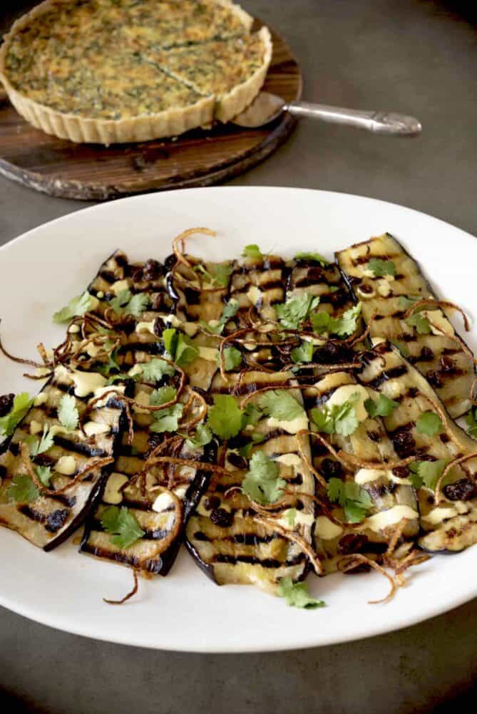 Sliced grilled aubergine/eggplant on a large white plate.