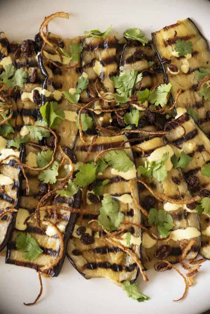 A close-up of grilled aubergine/eggplant with green coriander/cilantro leaves