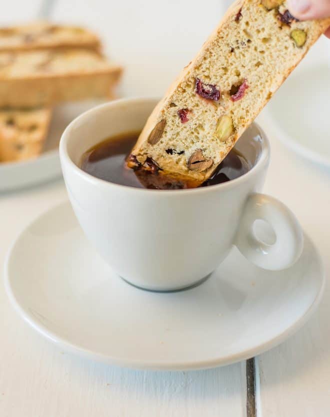 Dipping a cranberry orange pistachio biscotti into a cup of coffee