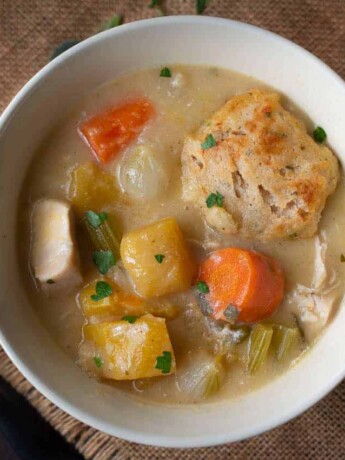 A bowl of creamy chicken stew with a sage and chive dumpling