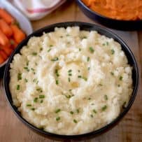Mashed potatoes in a bowl topped with butter and chives