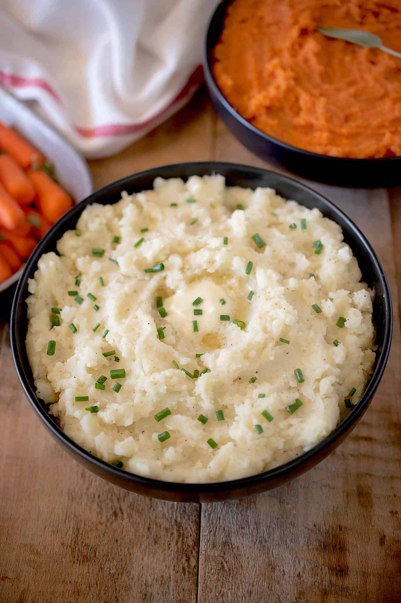 Mashed potatoes in a bowl topped with butter and chives