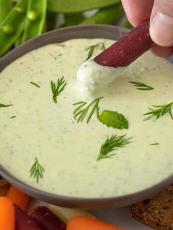 Dipping a carrot into creamy tzatziki dipping sauce