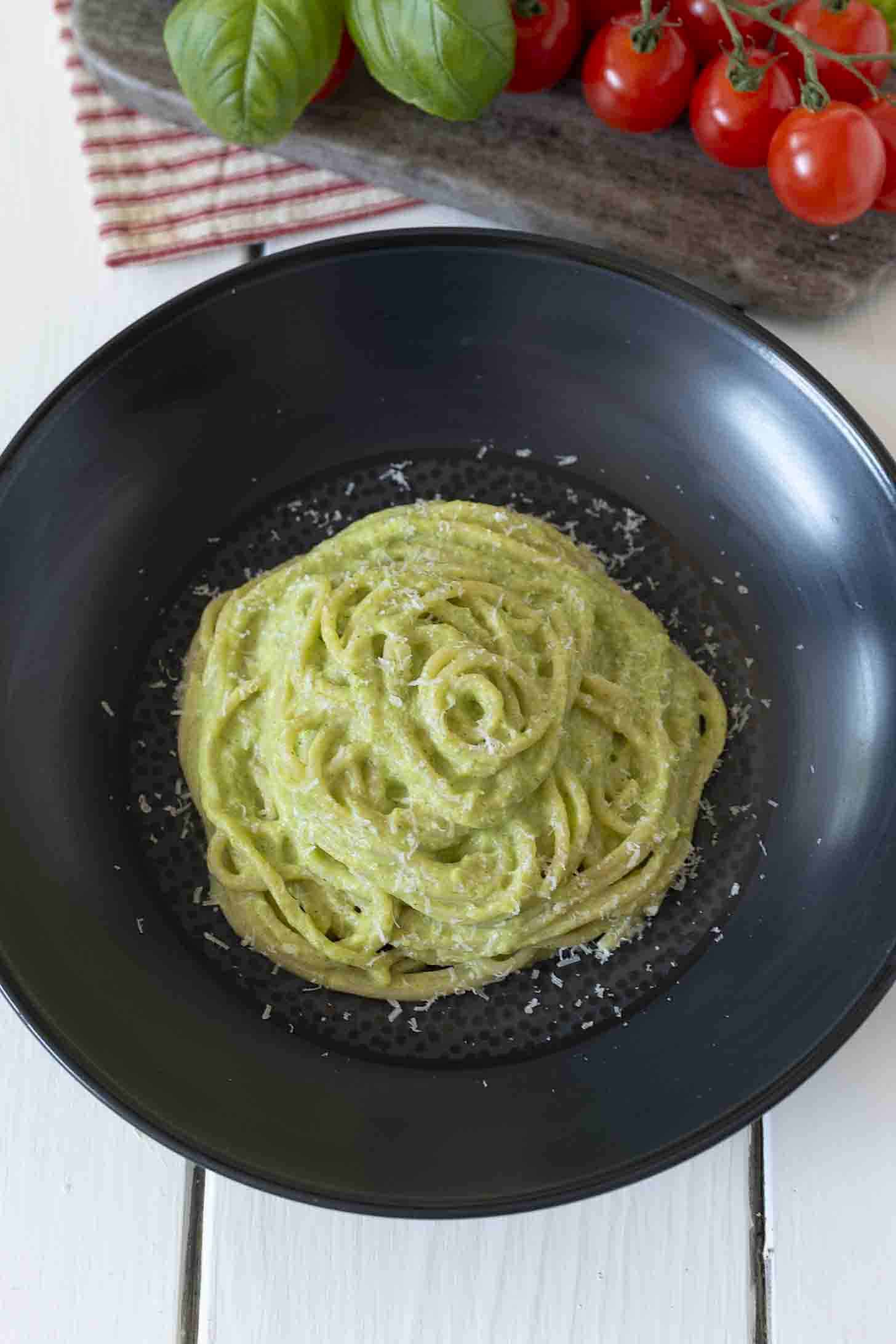 An overhead view of pasta sauce and spaghetti topped with grated Parmesan cheese in a black bowl