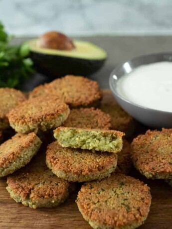 Brown and crispy falafel on a serving board with yogurt tahini sauce