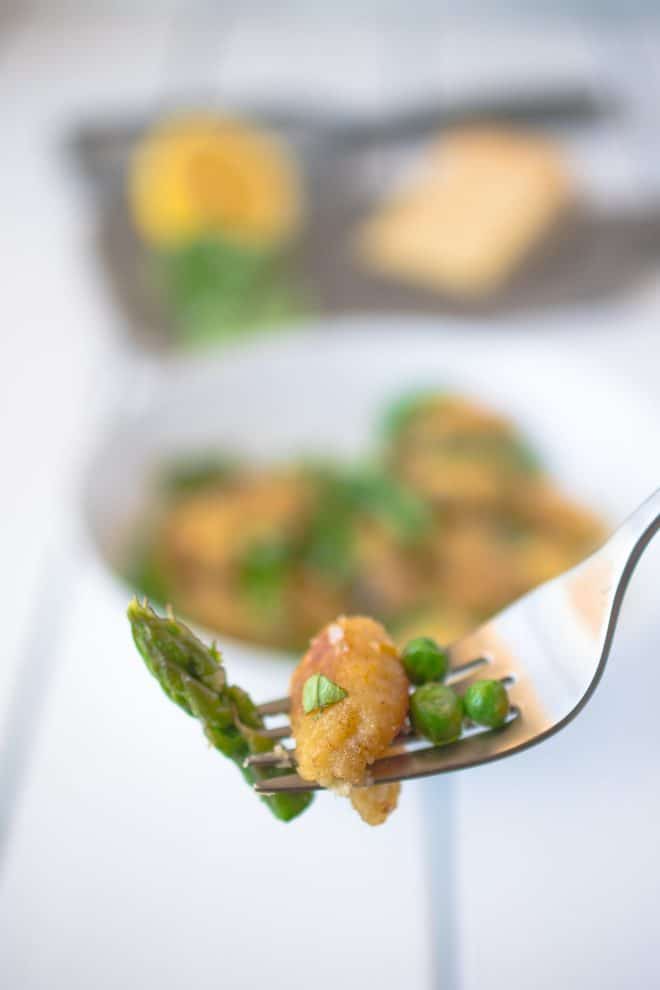 1 gnocchi on a fork with asparagus and peas