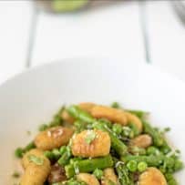 Fresh asparagus spear and peas mixed with gnocchi in a white bowl