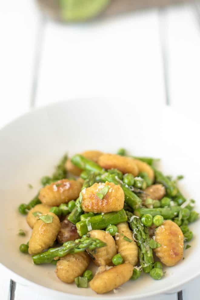 A closeup showing the brown and crispy gnocchi and vibrant green asparagus and peas