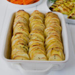 Thinly sliced potatoes lined up in roasting pan