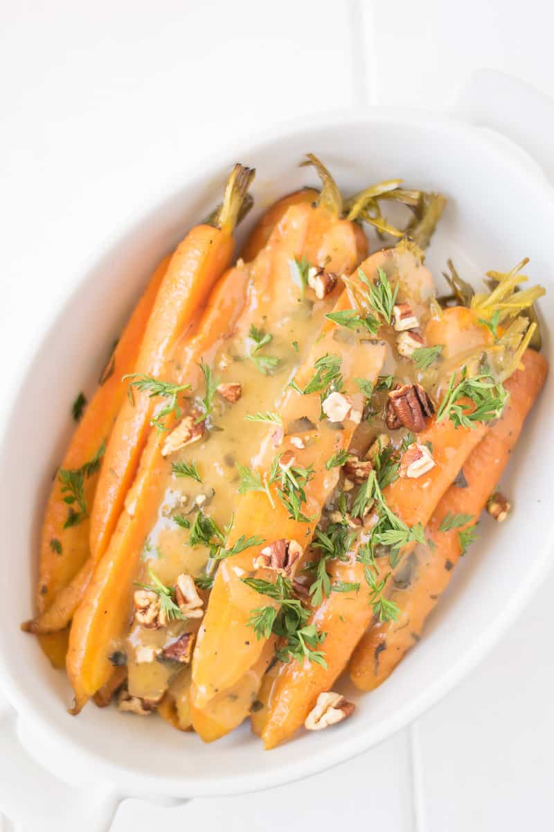 A bowl of slow cooked carrots with pecans and herbs
