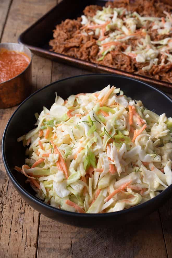 Crunchy vegetable coleslaw with vibrant orange carrot shreds and green scallions in a bowl