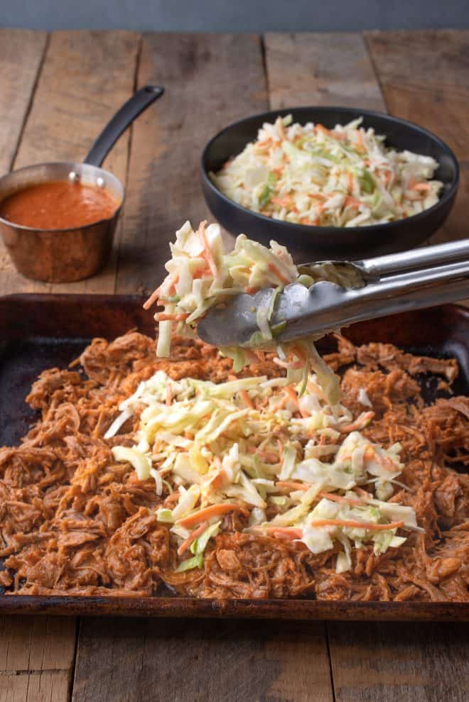 Topping a tray of pulled pork with crunch vegetable coleslaw