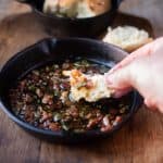 Dipping a piece of bread in to crispy bacon and sage in melted butter