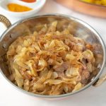 A copper bowl full of curry caramelized onions