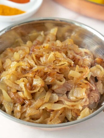 A copper bowl full of curry caramelized onions