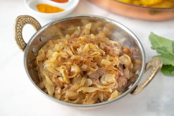 A copper bowl full of curry caramelized onions