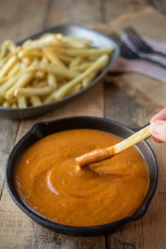 Dipping a French fry into a bowl of curry sauce