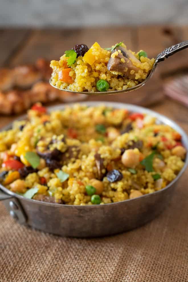A spoonful of curry quinoa with mushrooms, peas, carrots and raisins