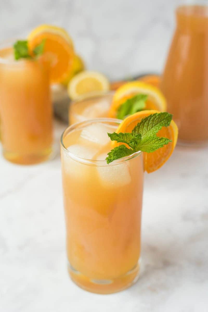 Earl Grey lemonade garnished with orange slice and fresh mint with a pitcher