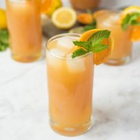 Earl Grey lemonade in a tall glass with fresh orange and mint