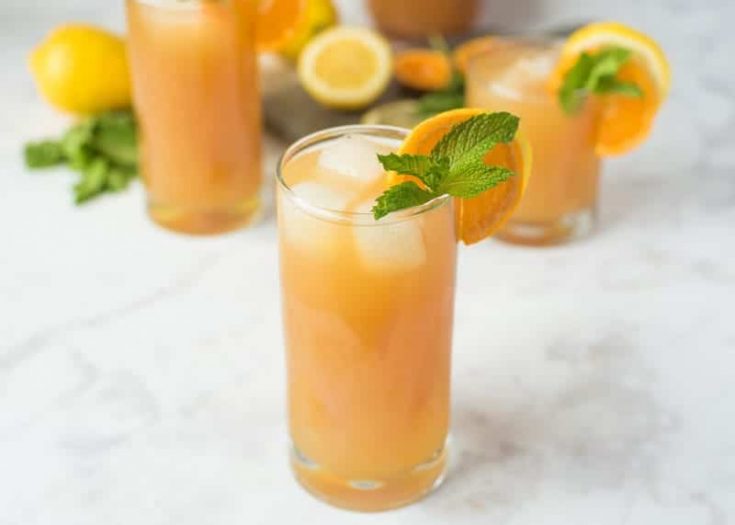 Earl Grey lemonade in a tall glass with fresh orange and mint